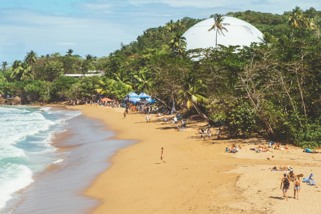 A vibrant beach scene in Rincón, Puerto Rico with people enjoying a sunny day by the sea.