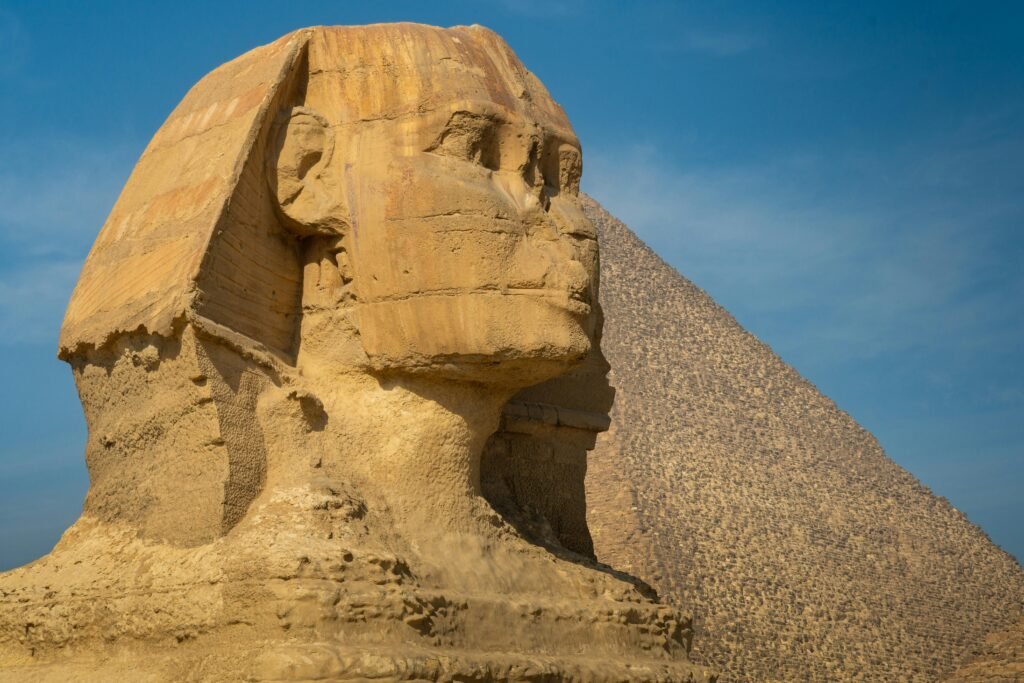 Iconic view of the Great Sphinx of Giza beside a pyramid under a clear blue sky.