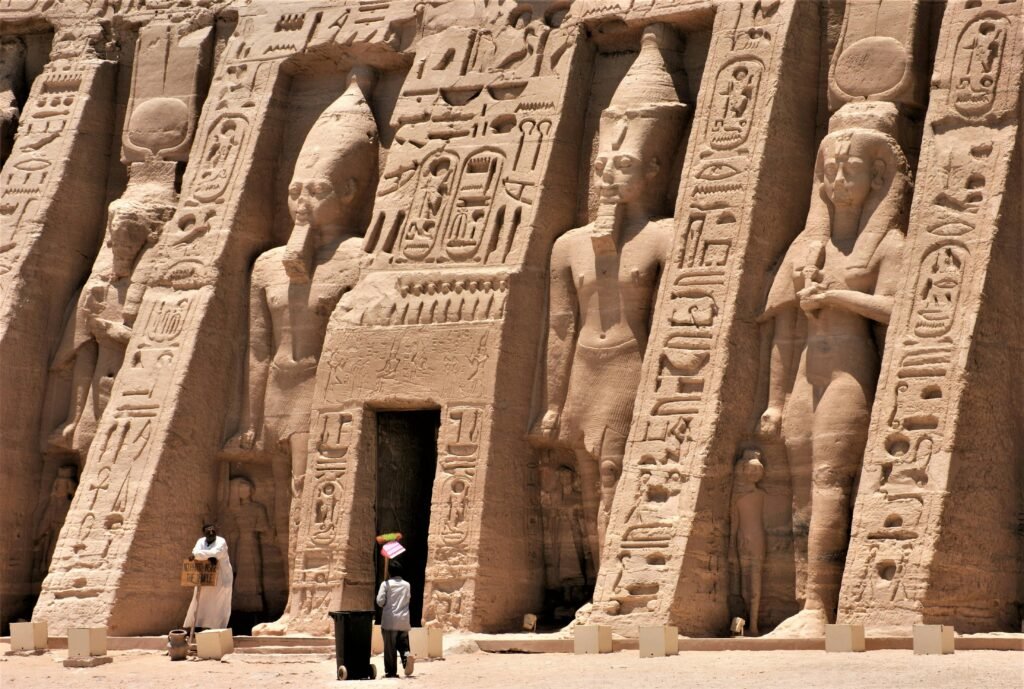 Exterior view of an ancient Egyptian temple featuring hieroglyphics and carved statues.